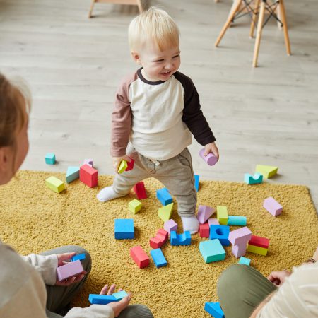 Child playing with toys on the floor together with his parents at home